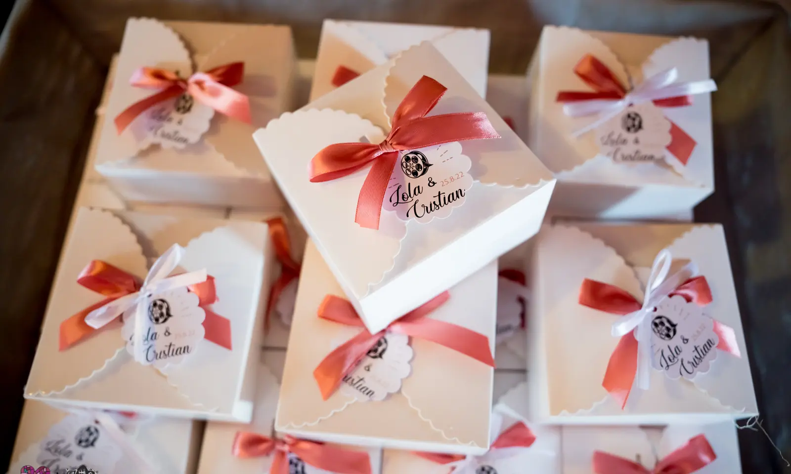Cajitas de regalo para los invitados con lazo coral y etiqueta personalizada