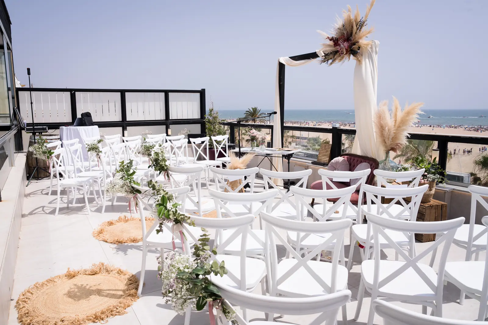 Ceremonia frente al mar con sillas blancas y pampas
