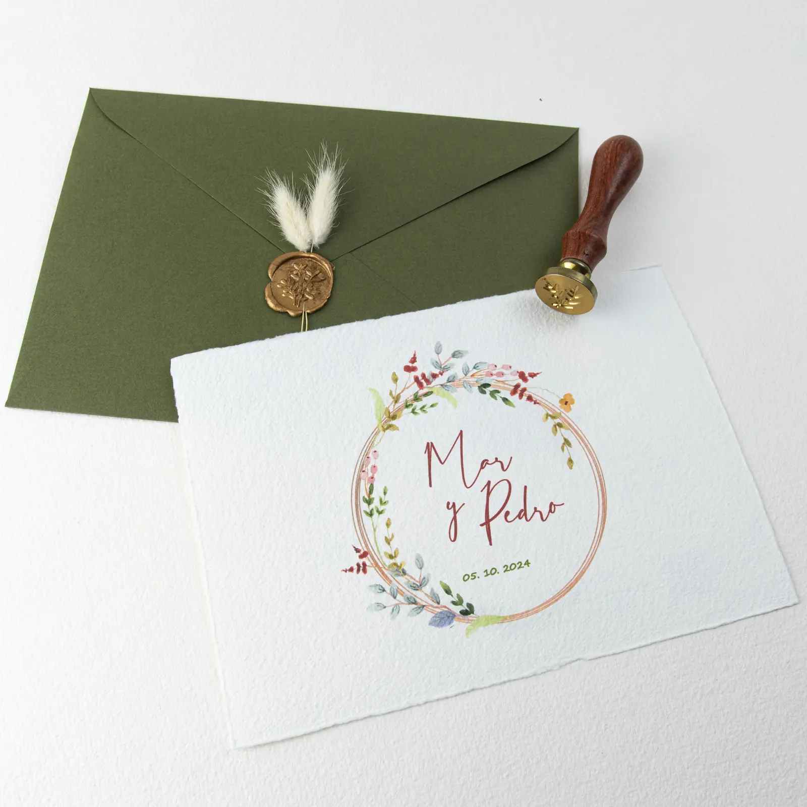Invitación de boda con corona floral, sobre verde y sello de lacre