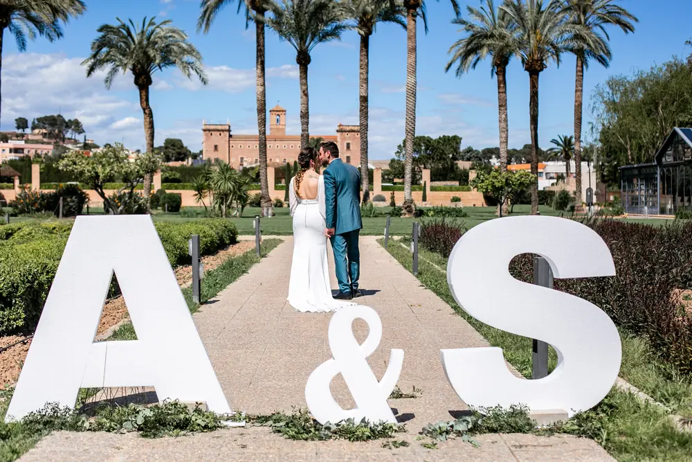 Letras gigantes con las iniciales de los novios en un paseo de palmeras